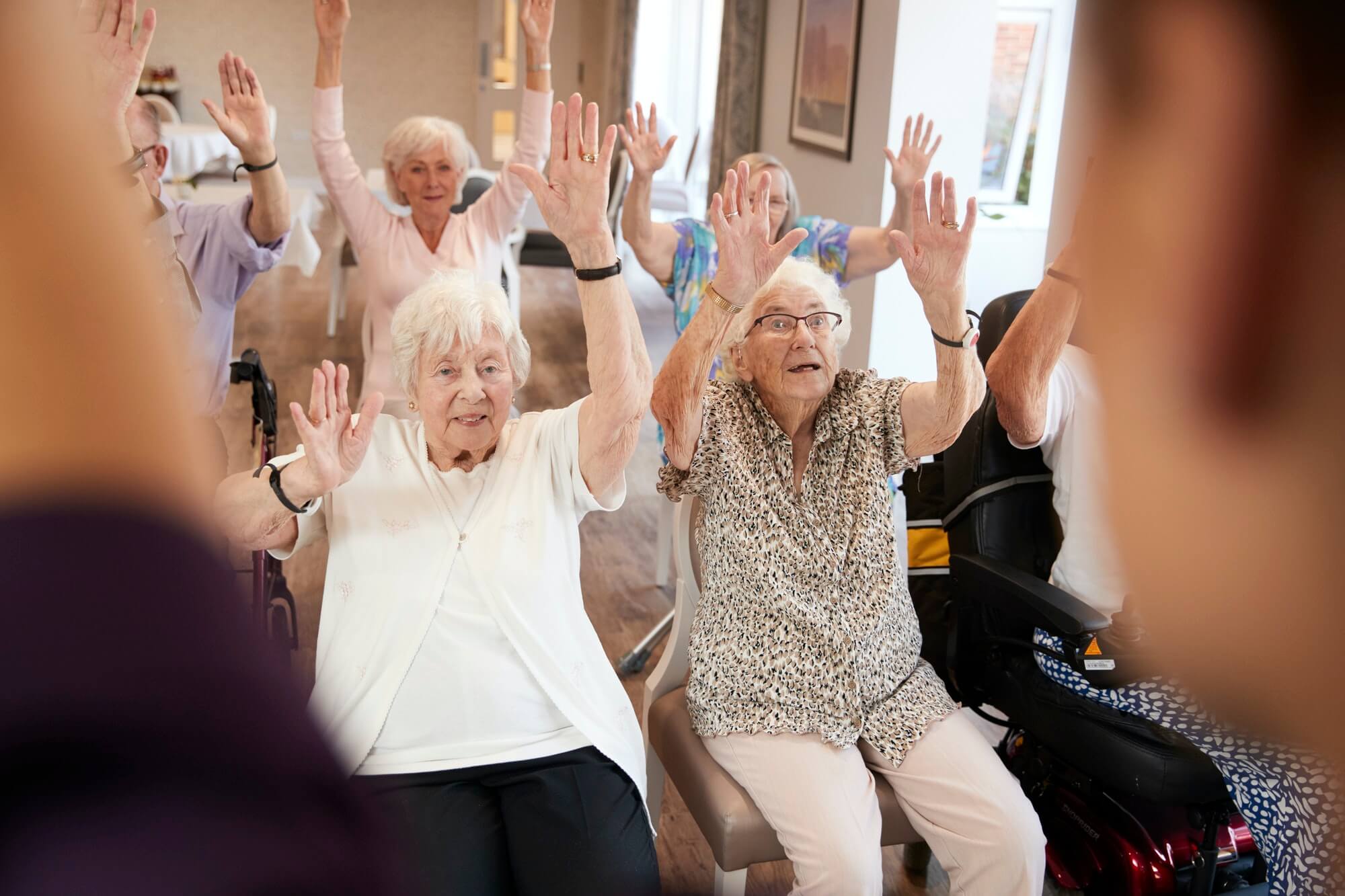 Carer leading a group of seniors in a fitness class in a retirement home